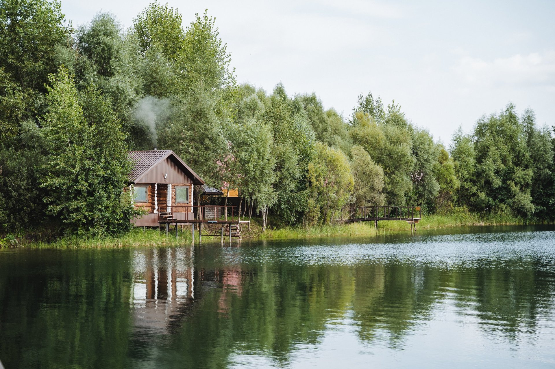 Cozy cabin on serene lake surrounded by trees at golden hour