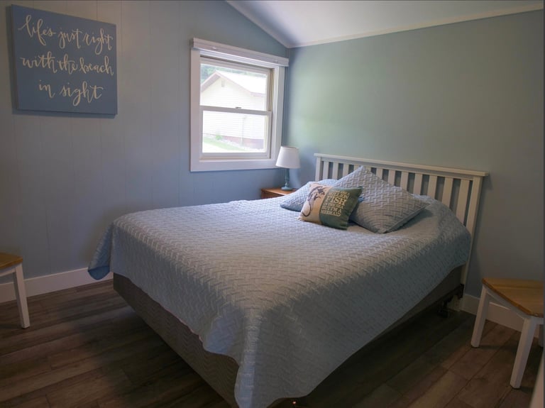 Cozy bedroom with white wooden bed, sage green walls, window, motivational wall sign, and wooden nightstands