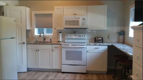 Modern kitchen with white cabinetry, stainless steel appliances, granite countertops, and wood flooring