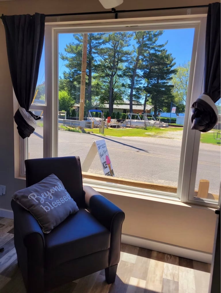Black armchair with blue cushion facing large glass doors overlooking a park with trees and lawn