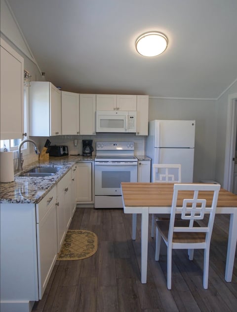 Modern kitchen with white cabinetry, stainless steel appliances, granite countertops, and dining table with chairs